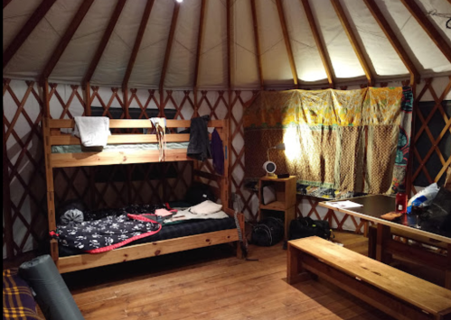 Interior of a yurt featuring a bunk bed, wooden furniture, and warm lighting, creating a cozy atmosphere.