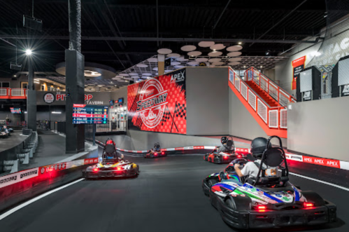 Go-karts racing on an indoor track with vibrant signage and a modern atmosphere.