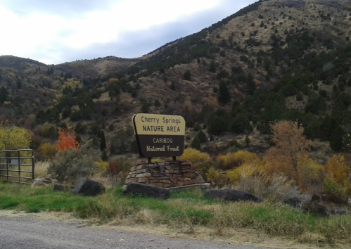 Sign for Cherry Springs Nature Area in the Carribou National Forest, surrounded by autumn foliage and mountains.