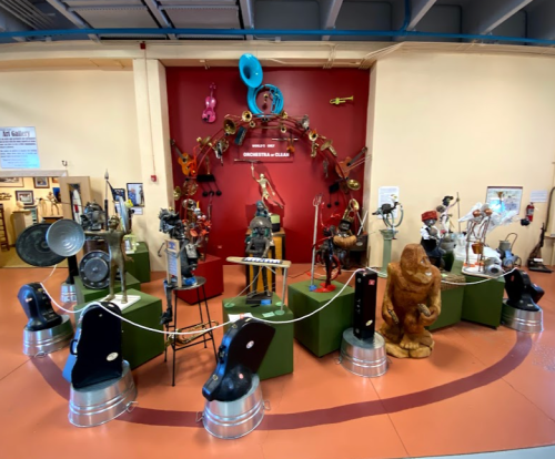 A display of various musical instruments and sculptures in a museum setting, featuring unique designs and arrangements.