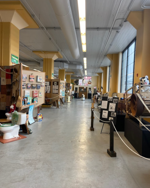 A spacious hallway in a gallery, featuring various art displays and exhibits along the walls.