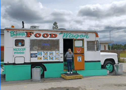 A colorful food truck named "Benny's Food Wagon" serving Mexican food, with a person ordering at the window.