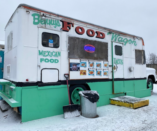 A colorful food truck with "Benny's Food Wagon" signage, serving Mexican food and tacos, parked in a snowy area.