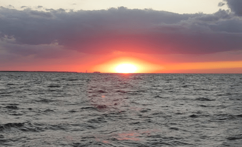 A vibrant sunset over the ocean, with colorful clouds reflecting on the water's surface.