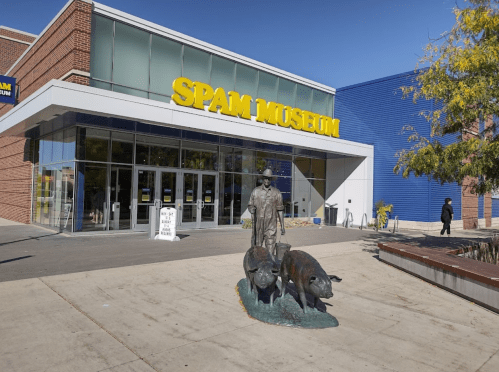 Exterior of the Spam Museum featuring a statue of a farmer with pigs in front of the entrance.