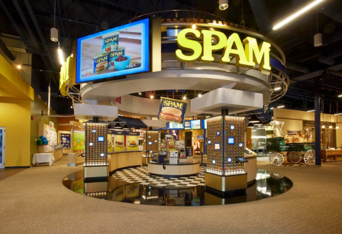 A vibrant exhibit featuring a large "SPAM" sign, showcasing products and information in a modern, spacious setting.
