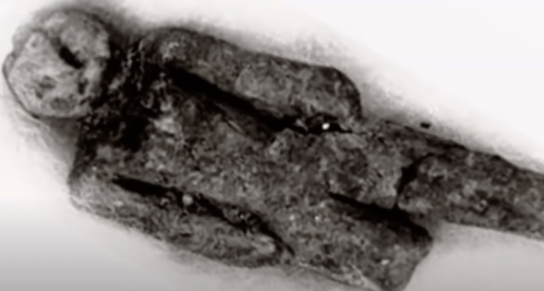 A small, ancient stone figure lying flat, showing a humanoid shape with minimal details.