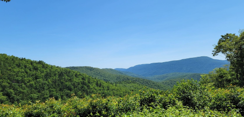 Lush green mountains under a clear blue sky, showcasing a serene natural landscape.