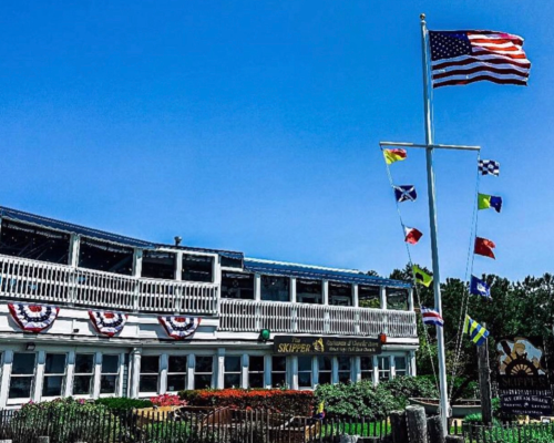 A waterfront restaurant with an American flag and colorful nautical flags, decorated for a festive occasion.