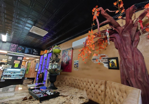 Cozy café interior featuring a tufted seating area, colorful decor, and a large tree sculpture with autumn leaves.