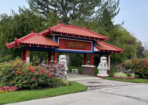 A traditional Chinese-style gateway surrounded by colorful flowers and greenery in a serene park setting.