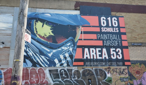 A large advertisement for Area 53 paintball and airsoft, featuring a person in a mask and goggles against a graffiti backdrop.
