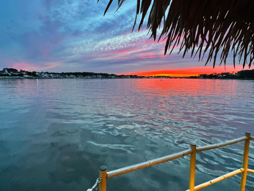 A serene sunset over a calm lake, with vibrant pink and purple hues reflecting on the water.