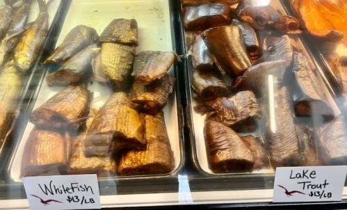 Smoked fish display featuring whitefish and lake trout, with price tags of $13 per pound.