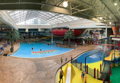 Indoor water park featuring a large pool, water slides, and play areas with children enjoying the attractions.