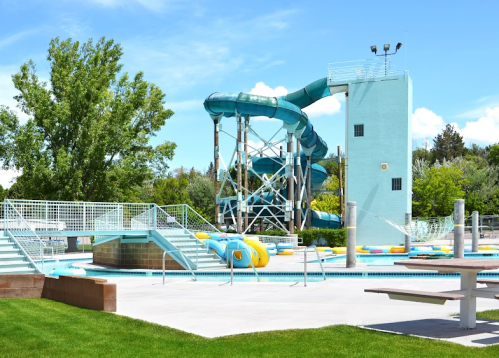 A water park featuring a tall blue waterslide, pool area, and colorful inner tubes on a sunny day.