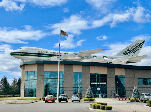 A large airplane model is mounted on a building, with an American flag and blue sky in the background.