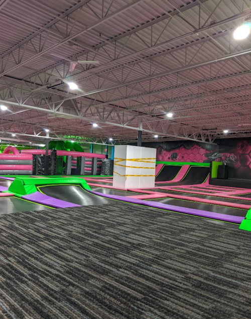 A vibrant indoor trampoline park featuring colorful trampolines, foam pits, and climbing walls.