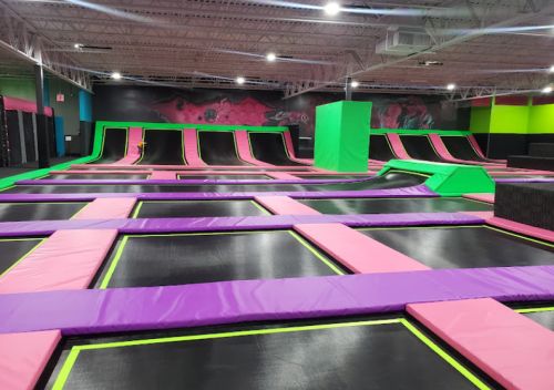 A vibrant indoor trampoline park featuring colorful trampolines, ramps, and foam pits.