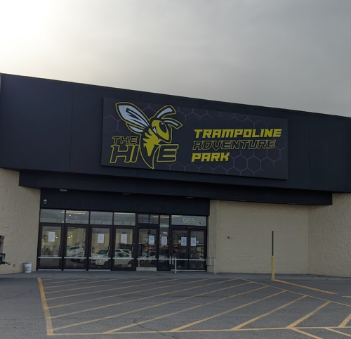 Exterior of The Hive Trampoline Adventure Park, featuring a large sign with a bee logo and entrance doors.