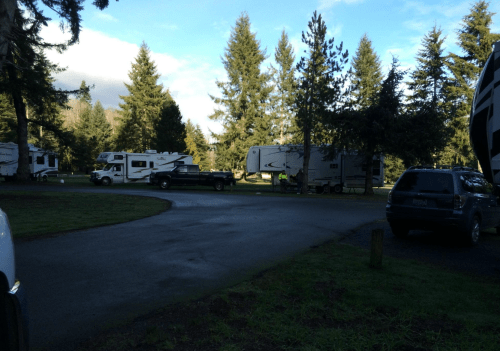 A scenic RV park with several RVs and trees under a partly cloudy sky.