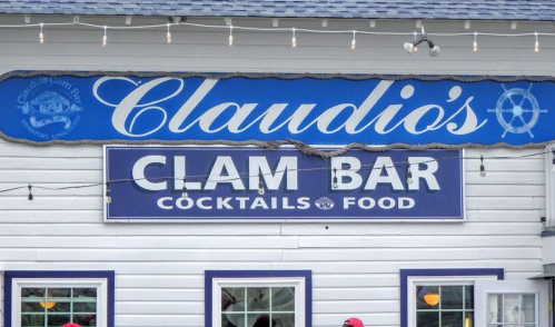 Sign for Claudio's Clam Bar, featuring "Cocktails" and "Food" with nautical-themed decor.