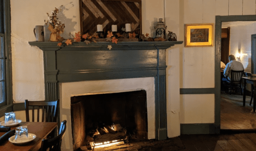 Cozy interior with a fireplace, autumn decor, and wooden furniture, creating a warm, inviting atmosphere.