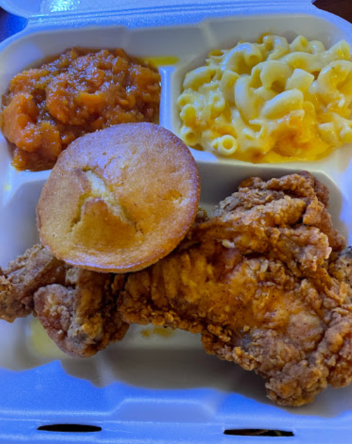 A takeout container with fried chicken, cornbread, macaroni and cheese, and sweet potato mash.