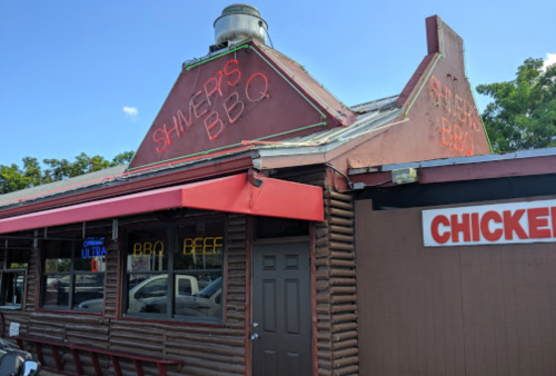Exterior of Shiner's BBQ restaurant with a red roof, neon signs, and a sign reading "Chicken" on the side.