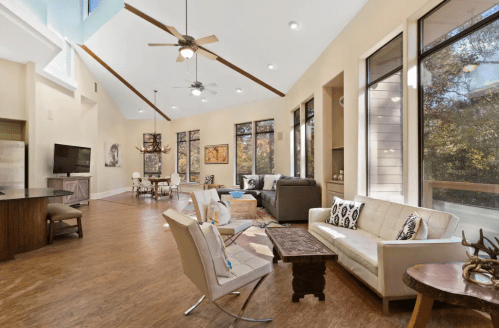 Spacious, modern living room with large windows, light wood floors, and stylish furniture. Bright and inviting atmosphere.