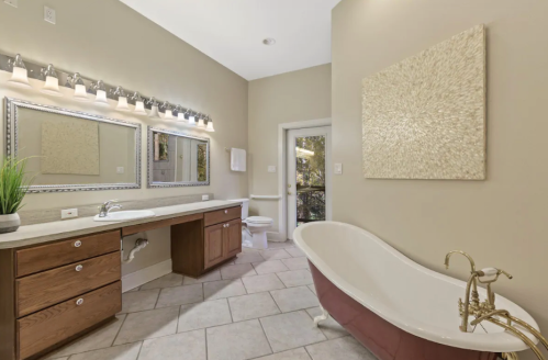 Spacious bathroom with a freestanding tub, double vanity, and large mirrors, featuring neutral tones and natural light.
