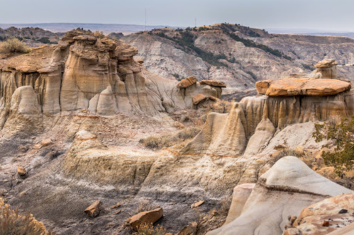 A rugged landscape featuring unique rock formations and hills under a cloudy sky.