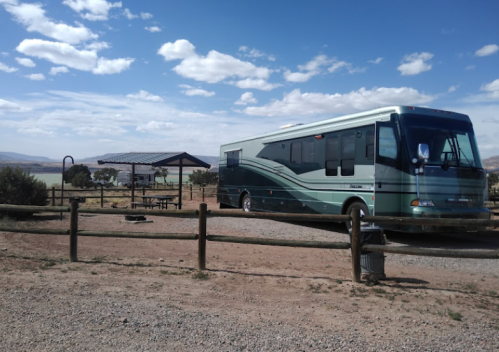 A parked RV at a campsite with a picnic area and blue sky in the background.