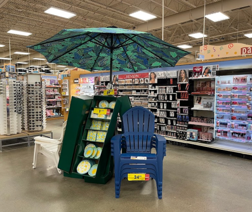A display featuring a large umbrella, beach chairs, and colorful plates in a retail store aisle.