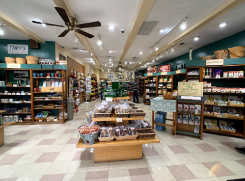 A spacious store interior with wooden shelves filled with various products and a central display of snacks and treats.