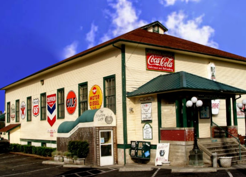 Historic building with vintage gas station signs, green awnings, and a welcoming entrance under a blue sky.