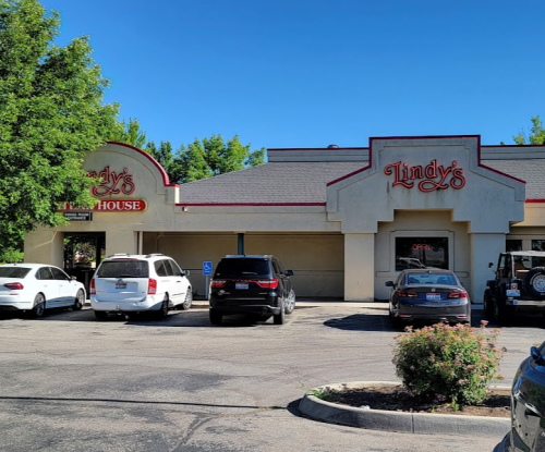 Exterior of Lindy's restaurant with a parking lot filled with cars and clear blue skies.