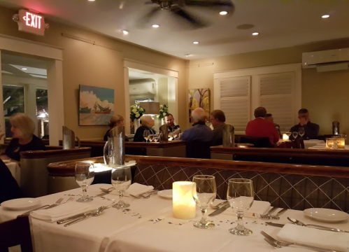 A cozy restaurant interior with dim lighting, tables set for dining, and patrons enjoying their meals.