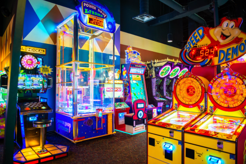 A vibrant arcade filled with colorful games, including a claw machine and various ticket redemption machines.