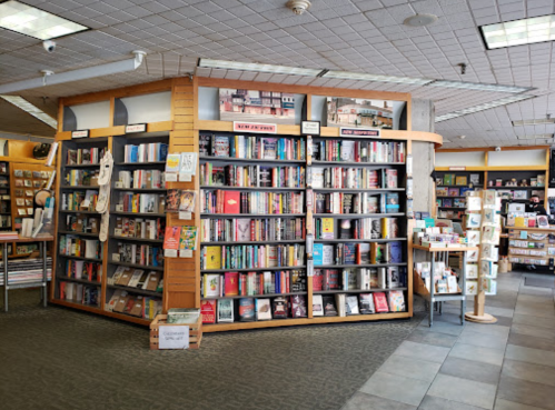 A cozy bookstore interior featuring shelves filled with books and a display of greeting cards.