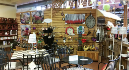 A cozy shop interior featuring wooden walls, decorative items, and tables with chairs, creating a warm atmosphere.