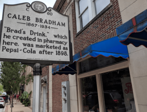 Historical marker for Caleb Bradham, creator of "Brad's Drink," later known as Pepsi-Cola, outside a brick building.
