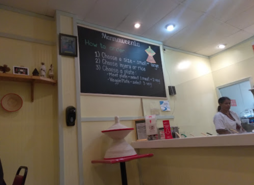 A cozy restaurant interior with a chalkboard menu on the wall and a staff member preparing food.