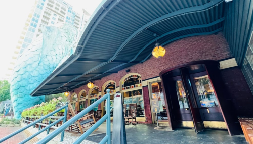 A building with a curved roof, featuring large windows and decorative lighting, surrounded by greenery.