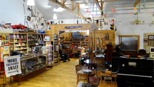 A cozy antique shop filled with vintage items, including furniture, toys, and collectibles, with wooden floors and warm lighting.