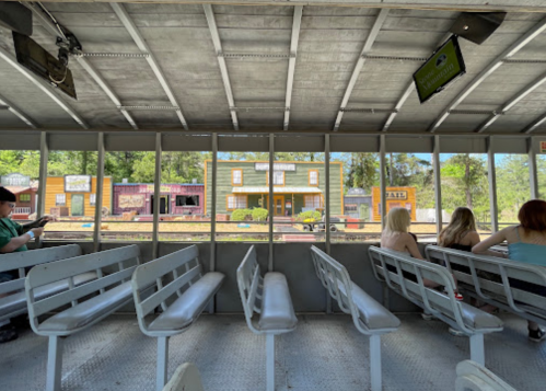 View from inside a boat with empty seats, looking out at colorful buildings along a riverbank.
