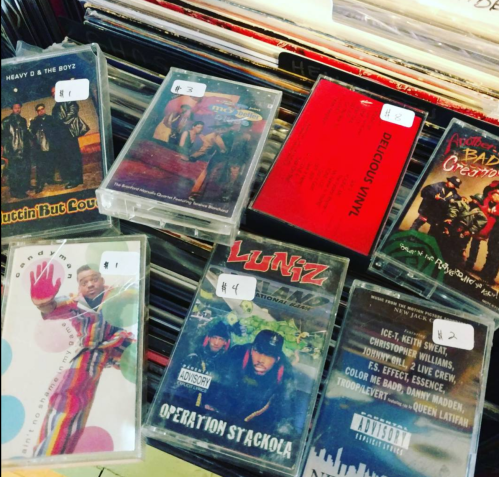 A collection of cassette tapes displayed on a shelf, featuring various artists and colorful covers.