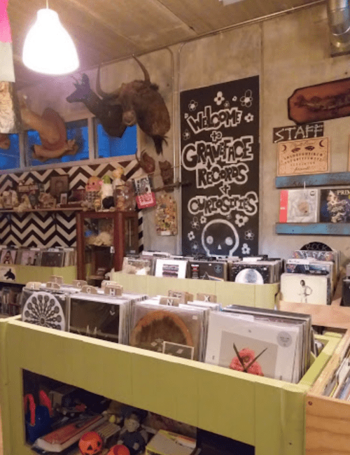 A cozy record store interior with vinyl records displayed, quirky decor, and a welcoming sign.