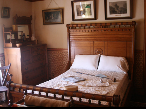 A vintage bedroom featuring a wooden bed, dresser, and decorative wall art, with soft lighting and a cozy atmosphere.