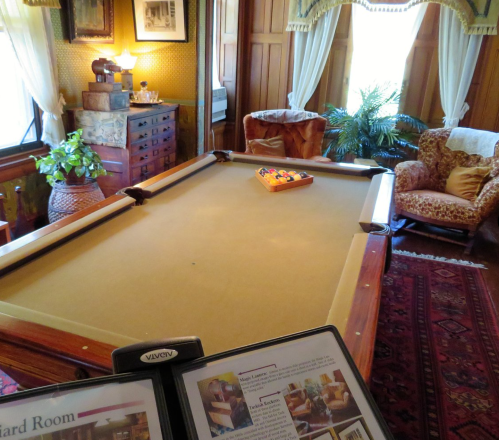 A cozy billiard room featuring a pool table, vintage decor, and comfortable seating.